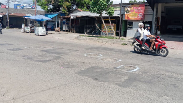 Salah satu diantara beberapa lubang yang mengaga, ditandai pilox oleh warga. (Foto/Feri)